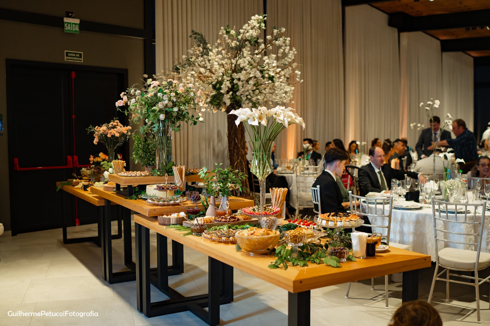 Mesa de buffet com arranjos altos de calas e flores